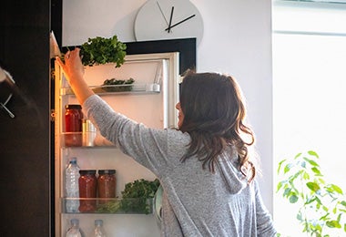 Mujer sacando ingrediente de refrigerador, quitar mal olor del refrigerador