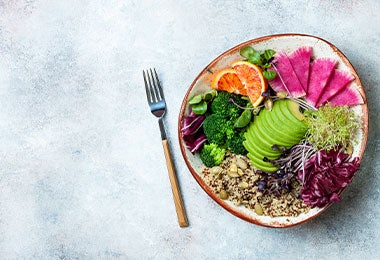 Bowl vegano. Buddha bowl vegano con quinoa, microvegetales, aguacate, naranja sanguina, brócoli, rábano sandía y brotes de alfalfa. Vista superior, plano, espacio para copiar.