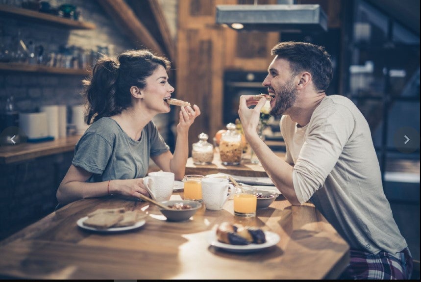 Pareja comiendo sándwiches, uno de los desayunos fáciles y rápidos