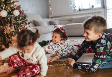niños jugando junto al árbol de navidad