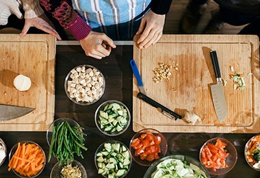 Mesa con tabla de corte y bowls con verduras recién picadas. 