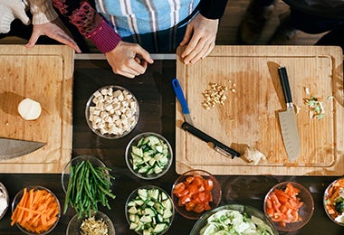 Mesa con tabla de corte y bowls con verduras recién picadas. 