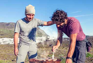 Dos amigos cocinando asado de tira.