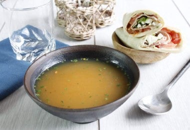 Plato hondo con caldo de hueso de pollo acompañado de wraps