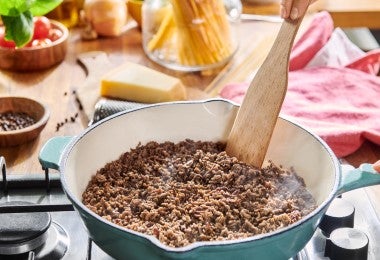 Cocción de carne molida en sartén mientras se revuelve, elemento esencial para el huevo escocés.