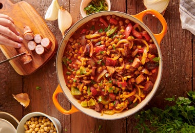 Cassoulet servido en olla con alubias, salchichas y vegetales frescos