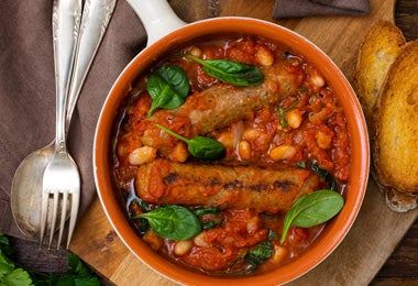 Cassoulet con salchichas, alubias y salsa de tomate servido en sartén
