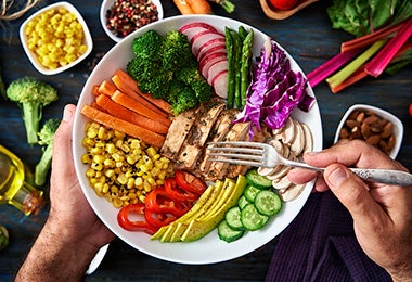  Plato con zanahoria, maíz, brócoli y espárragos cocinados al vapor, junto a otros alimentos.