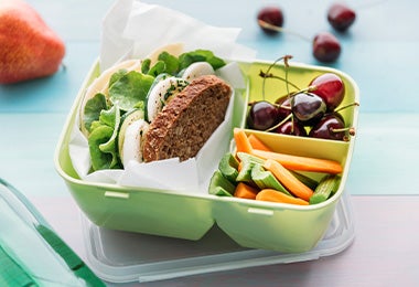 Un sándwich con frutas picadas y uvas, tres comidas para viajes deliciosas.