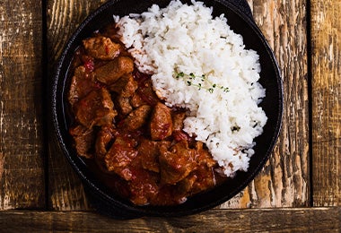 Arroz blanco y carne, comidas fáciles de hacer, servidos en un plato negro.