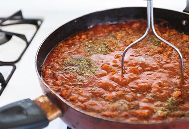 Frijoles en una sartén, sazonados con hierbas aromáticas y sal.
