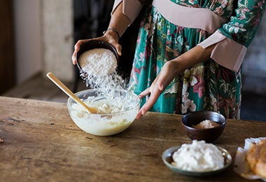 Mujer añadiendo harina a su mezcla de crema pastelera.