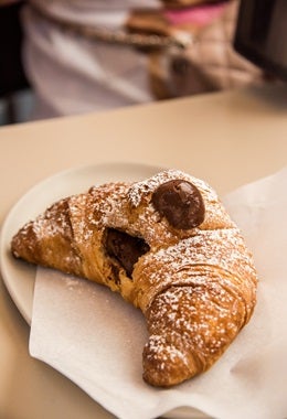 Delicioso croissant relleno de chocolate y espolvoreado con azúcar pastelera, similar al croissant de almendras.