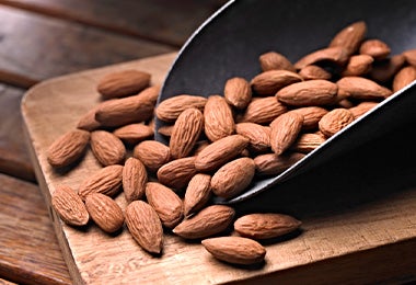 Cuchara y tabla con almendras enteras para pelar