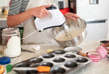  Mujer mezclando masa de muffins frente a una mesa con moldes de silicón.