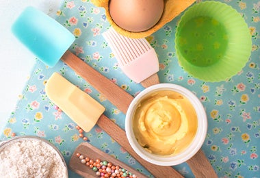 Utensilios de repostería como una brocha, un molde y unas espátulas de silicón sobre un mantel azul