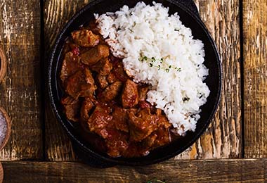 Una carne que pasó por un proceso de cocción mixta, acompañada de arroz.