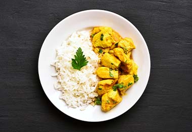 Un pollo estofado al curry, acompañado de arroz.