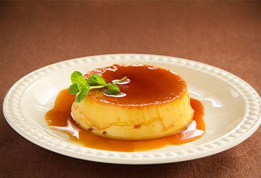 Flan típico de la gastronomía mexicana con hoja de hierbabuena y salsa de caramelo.