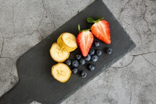 Tabla con fresas, arándanos y bananos en desayuno continental 