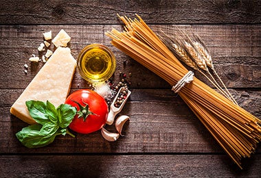 Vista superior de espaguetis con ingredientes para cocinar pasta, composición tomada sobre una mesa de madera rústica.