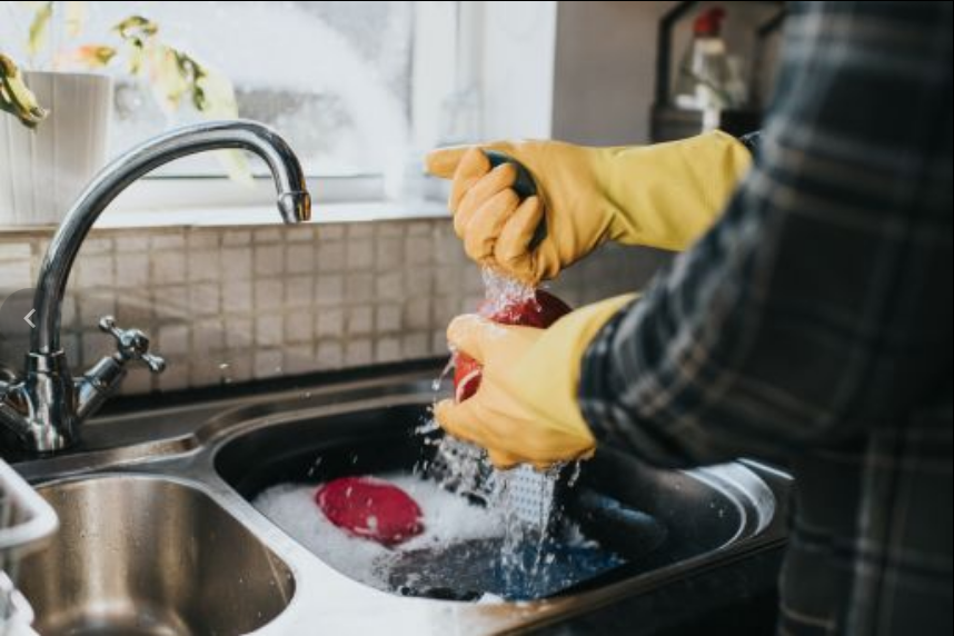 Un hombre lavando utensilios de cocina