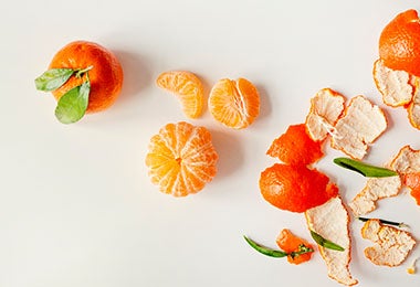 Mandarina en gajos y cáscaras y hojas de mandarina. 