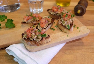 Montaditos con atún, tomate fresco y hierbas, servidos en tabla