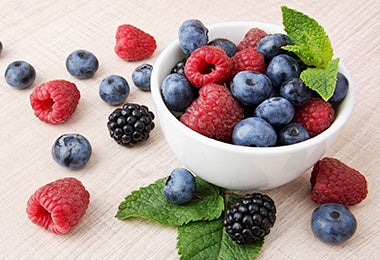 Un bowl pequeño lleno de moras azules y frambuesas.