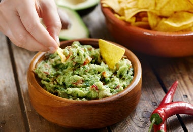Persona dipeando en una mezcla de nachos para rellenar el bolillo.