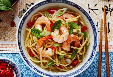 Noodles con camarones y especias, servidos en un plato de origen asiático.