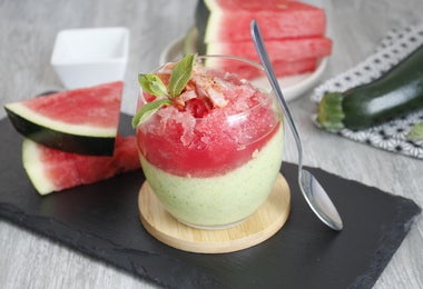 Vaso de panna cotta de frutas tropicales junto a pedazos de sandía.