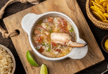 Plato de caldo de pescado con cangrejo, arroz y chips de plátano