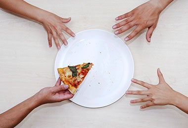 Plato con pizza y manos para calcular porciones de alimentos