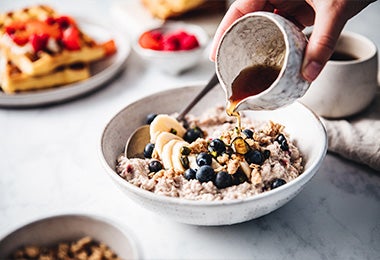 Plato de porridge con plátano, moras azules y miel