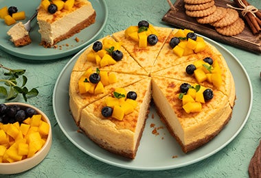 Un pay de mango con base de galletas y decorado con frutas.