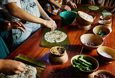 Mujeres preparando la masa del tamal de pescado sobre hoja de plátano.