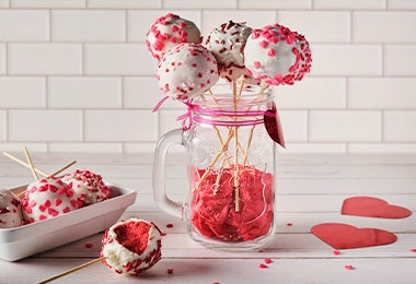 Recipiente con cake pops en una mesa de dulces