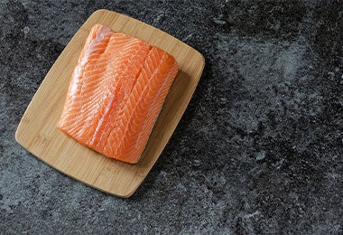 Filete de salmón, tipo de pescado azul, sobre tabla de picar.