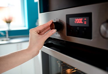 Mujer graduando la temperatura de su horno para calentar waffles 