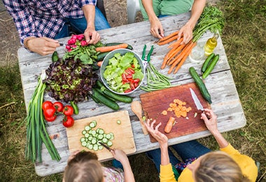  Familia partiendo verduras con diferentes tipos de corte para preparar una ensalada. 