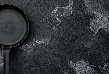 Sartén antiadherente de titanio sobre superficie negra corrugada.