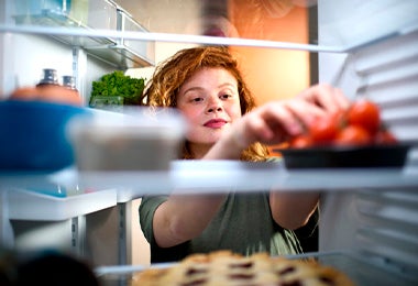 Mujer sacando tomates del refrigerador