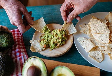 Manos agarrando totopos con guacamole