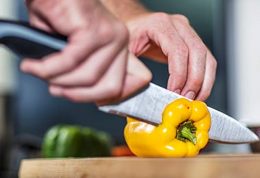 Una persona cortando un pimiento con un cuchillo, un utensilio clave para un asado.