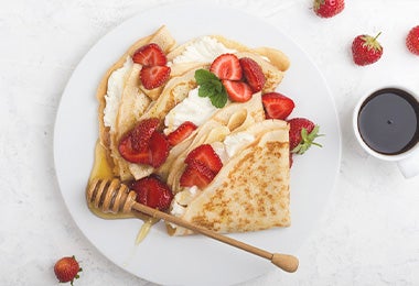 Waffle con fresas, crema, miel y hierbabuena, una comida con calorías que puedes consumir.