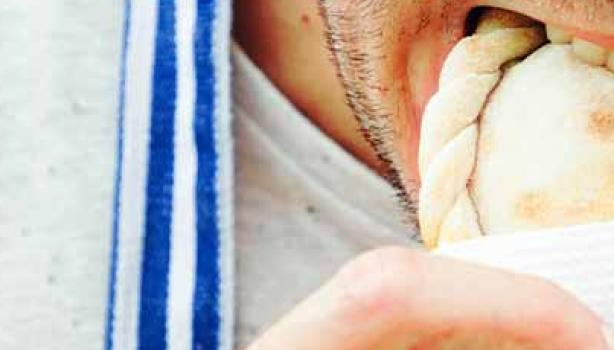 Un hombre comiendo una empanada tucumeña, una clase de empanada argentina.