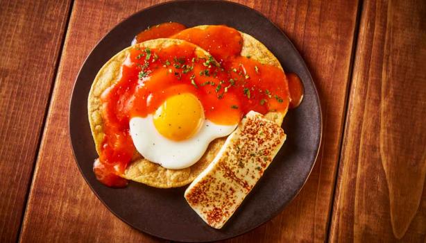 Un desayuno con huevo, tortillas y salsa. 