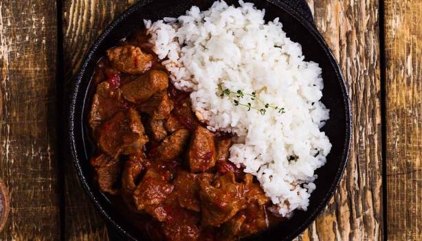 Carne en cuadros y arroz blanco en una sartén de hierro.