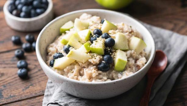 Plato de porridge con moras azules y manzana verde